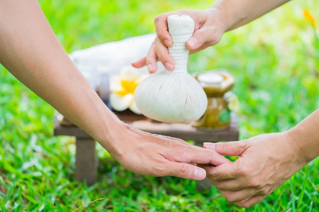 Female hands with tray of spa products over green reeds on river