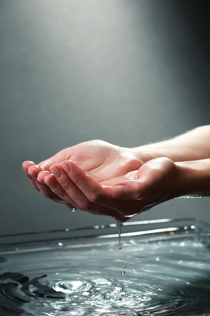 Female hands with water splashing on dark background