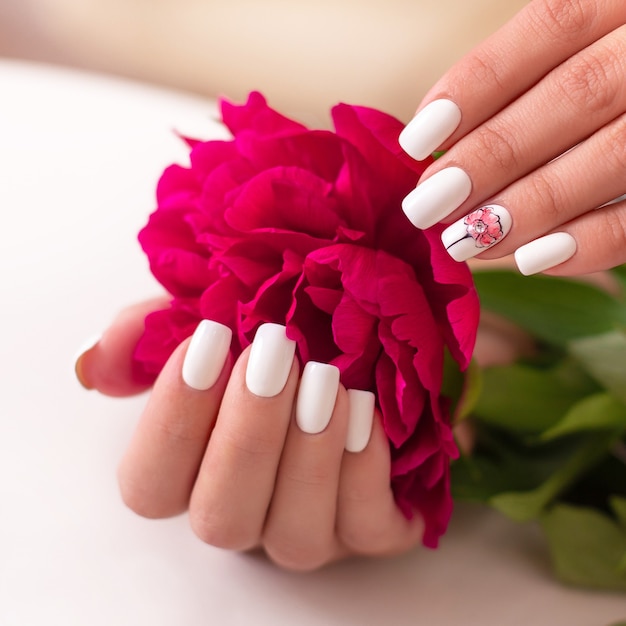 Female hands with white manicure nails peonies design