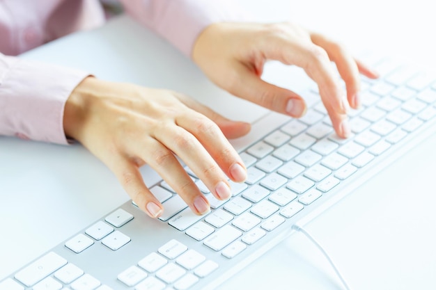 女性の手や女性の事務職員がキーボードでタイピングしている