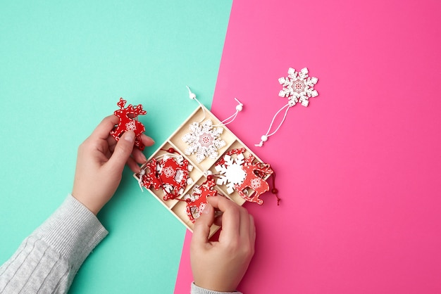 female hands and wooden carved Christmas decorations for the holiday tree