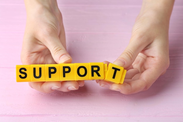 Photo female hands and word support on wooden background