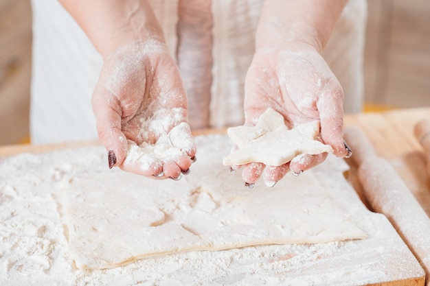 Mani femminili che lavorano con la pasta per fare i biscotti