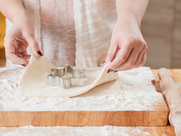 Mani femminili che lavorano con la pasta per fare i biscotti