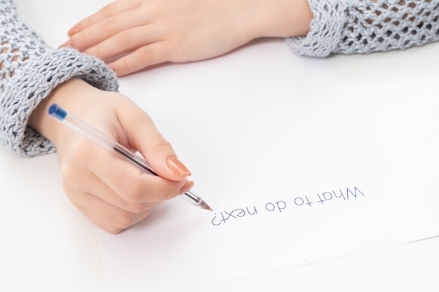 Female hands write on a sheet of paper what to do next