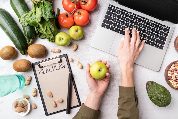 Female hands writing in the notepad words meal plan top view flat lay