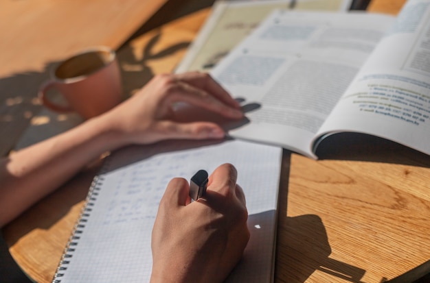 写真 ノートにペンで書く女性の手やアカデミック教科書で勉強するメモを取るプランナー...