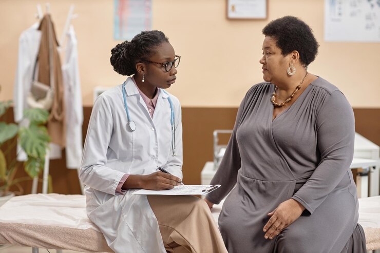 Female health practitioner listening to patient in clinic