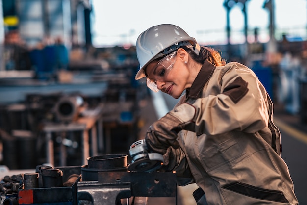 Foto il lavoratore dell'industria pesante femminile in lavoro protettivo indossa il metallo stridente.