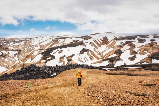 Женщина-туристка, путешествующая по холму по тропе Бреннистейнсалда с вулканической горой и заснеженным ландшафтом Ландманналаугар в высокогорье Исландии