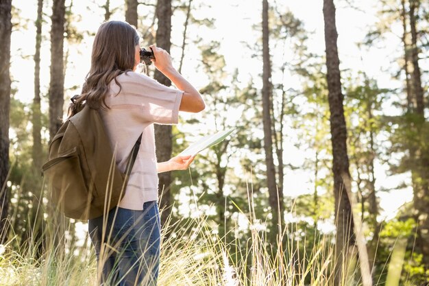 Foto viandante femminile che osserva tramite il binocolo