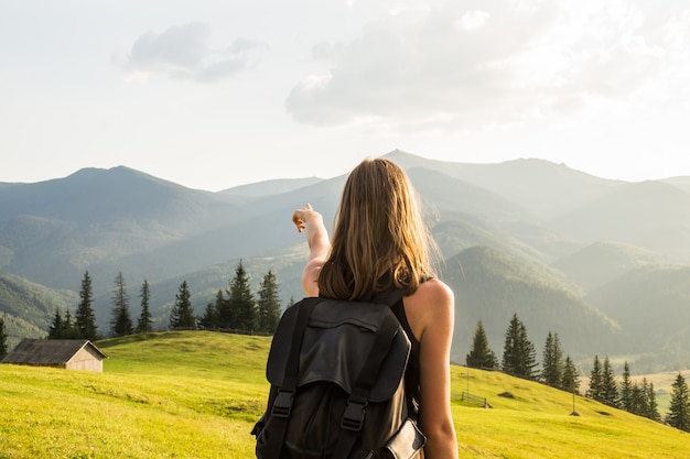 女性ハイカーは、山の旅の目的地を指す