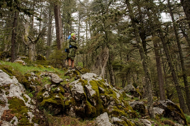 Female hiker in raincoat stands on cliff