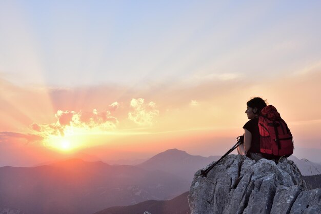 female hiker resting and watching the sunset