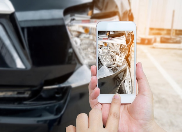 Foto smartphone mobile della tenuta femminile che fotografa l'incidente d'auto per l'assicurazione