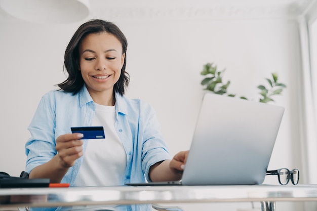 Female holding bank credit card uses online banking services on
laptop e commerce ebusiness