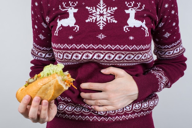 Female holding bitten sandwich in hand and suffering from acute stomach ache