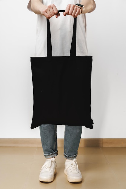 Female holding black cotton bag in her hands on white background