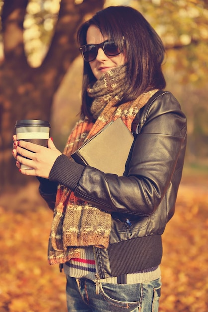 一杯のコーヒーと本を保持している女性