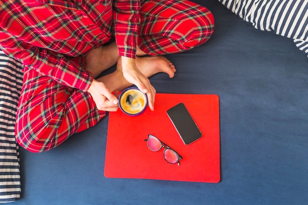 Female holding cup sitting on bed