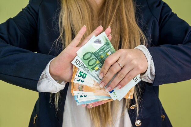 Female holding euro in her hands isolated on green wall