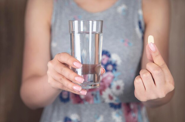 水と薬のガラスを保持している女性