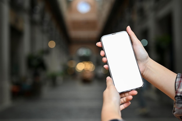 a female holding a mobile phone over blurred community mall in the background
