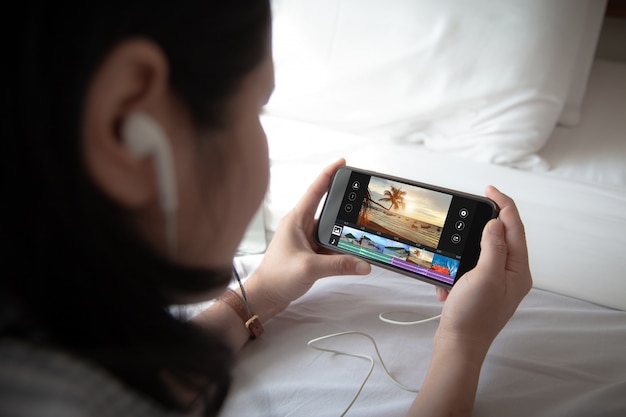 Female holding mobile phone and wearing ear phone