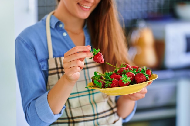 집 부엌에서 신선하게 익은 유기농 딸기를 든 여성용 접시