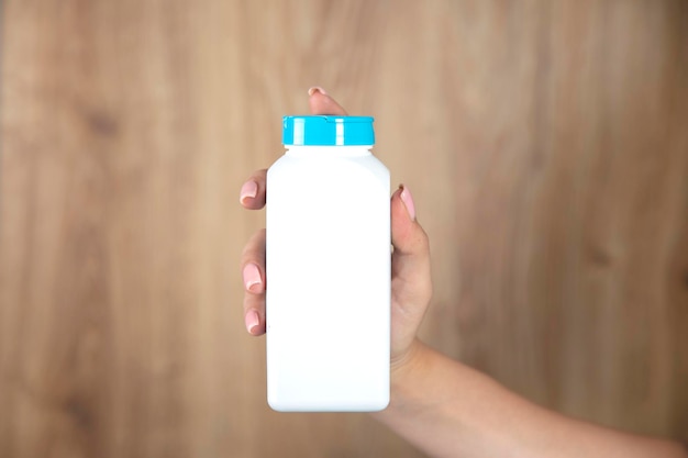 Female holding a white plastic medicine bottle