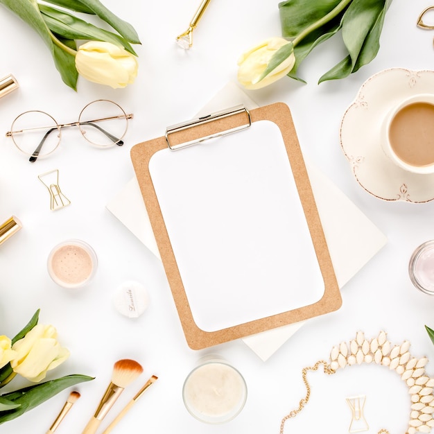 Foto spazio di lavoro femminile per l'ufficio domestico con accessori dorati per appunti da donna, fiori di tulipano giallo, cartoleria