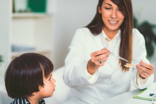 Photo female homeopath giving medicine to boy at clinic