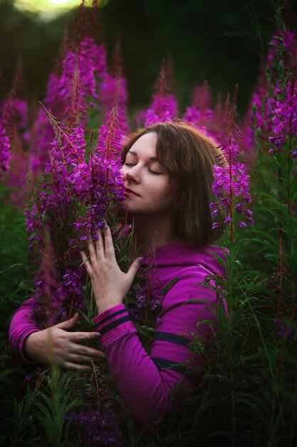 牧草地の花に囲まれたパーカーの女性