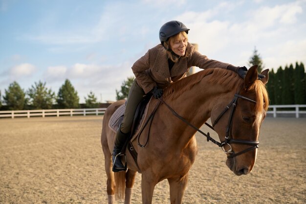 Female horse trainer with her stallion outdoors spending time at countryside farm. Horsewoman on rancho