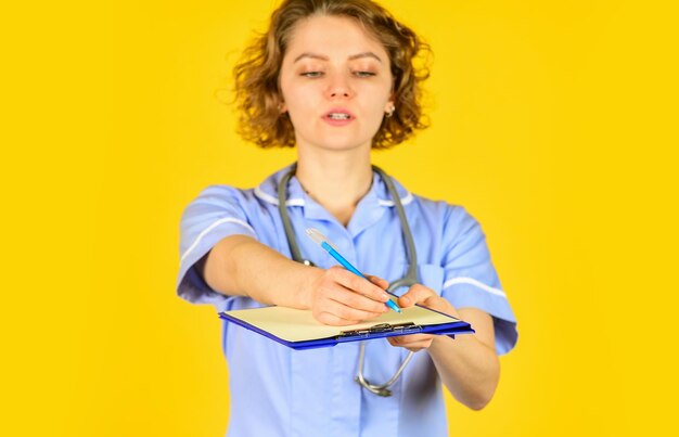 Female hospital administrative in a modern medical center nurse in medical coat with documents writes important information nurse writing some data into the folder of papers selective focus