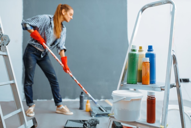 Female house painter paints walls indoor. 