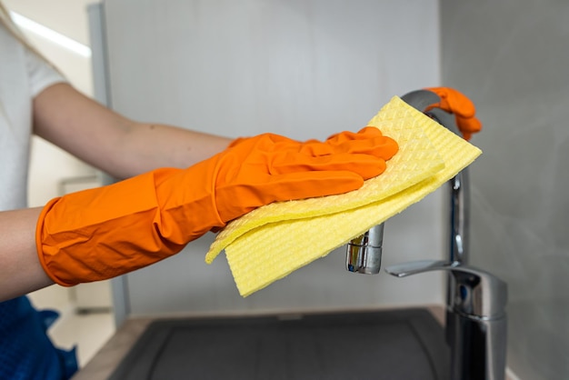 Female housekeeping hands in gloves cleaning counter top in kitchen close up cleaning concept