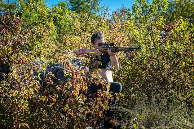 Female hunter in top using weapon or rifle at nature, outdoor