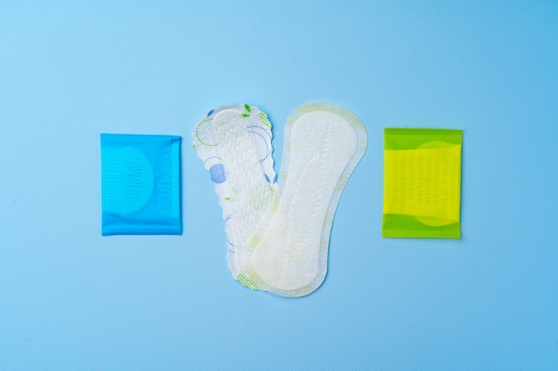 Female hygienic pad and tampons on blue background top view