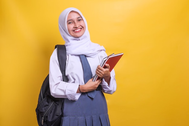 Female Indonesian high school student in white and grey uniform holding books