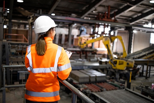 Female industrial worker controlling production in factory