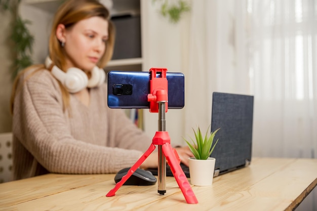 Foto influencer femminile che vlogga online con una telecamera per smartphone e un portatile