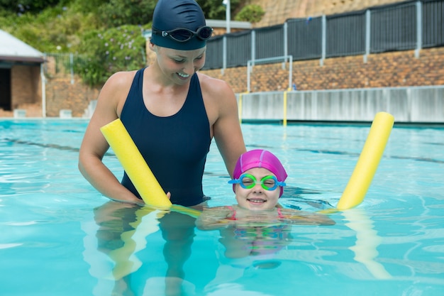 Female instructor training young girl in pool