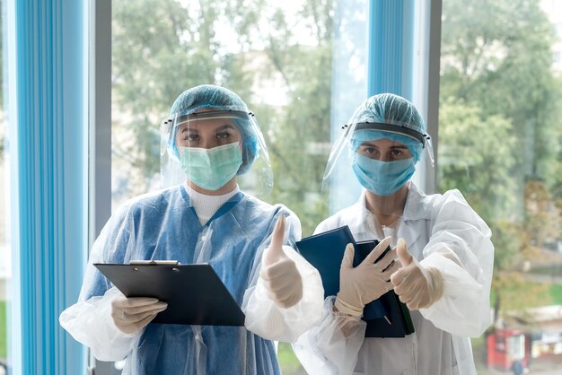 Female intern doctor in corridor of modern clinic in protective clothing during coronavirus pandemic