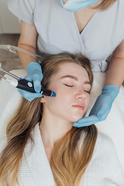 La donna sta ricevendo la pulizia sollevando il ringiovanimento idratando il trattamento del viso nella clinica di bellezza