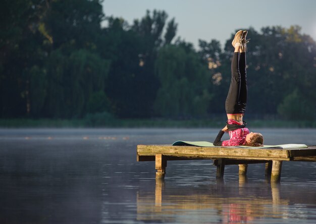 Foto la femmina sta praticando yoga sul lago. concetto di sport e stile di vita