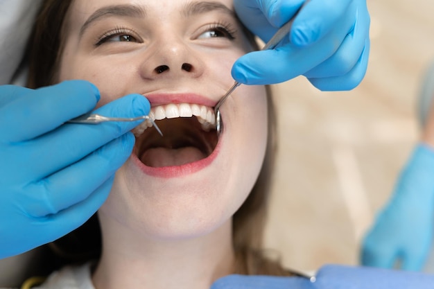 Женская челюсть заделывают. Руки врача стоматолога с инструментами. Концепция лечения кариеса