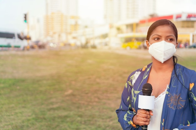 Female journalist talking over microphone while standing on street in city