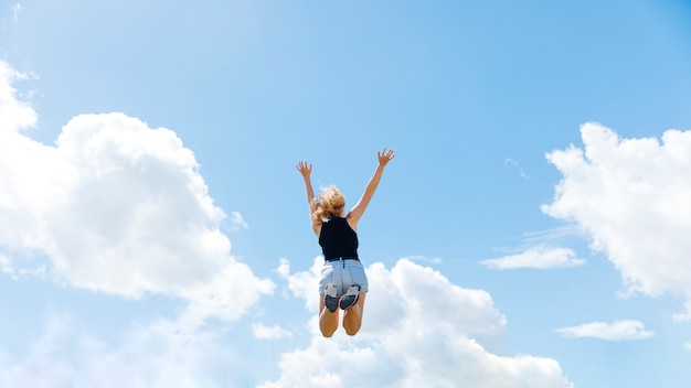 青い空を背景にジャンプ女性