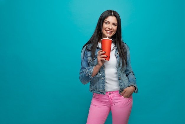 Female keeping one hand in pocket and drinking lemonade